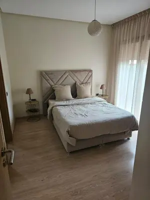 a bedroom with a large bed with two tables and two lamps at Bel appartement avec piscine et jardin in Marrakech