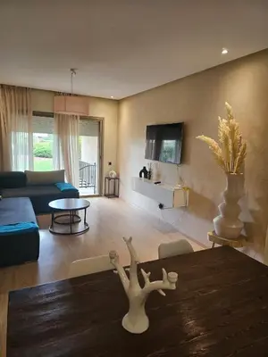 a living room with a table and a couch at Bel appartement avec piscine et jardin in Marrakech