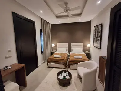 a bedroom with two beds and a chair in it at Riad Sabrawa in Marrakech