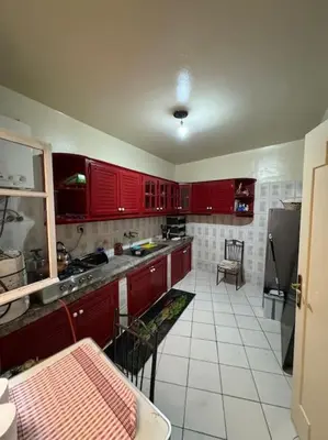 a kitchen with red cabinets and a white tile floor at appartement Holiday relais près musée Saint-Laurent in Marrakech