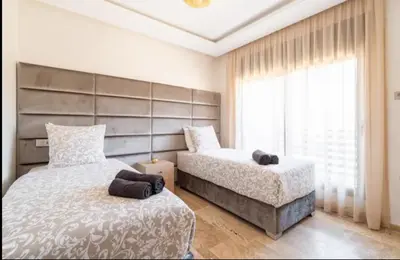 a bedroom with two beds and a large window at Appartement gueliz in Marrakech