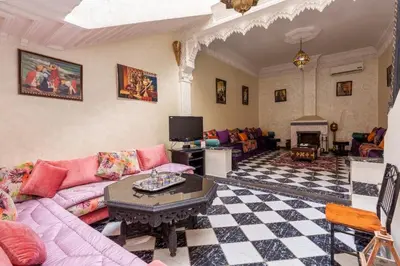 a living room with a pink couch and a fireplace at Riad Malika in Marrakech