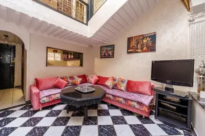 a living room with a red couch and a flat screen tv at Riad Malika in Marrakech