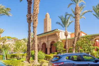 a car parked in front of a building with palm trees at Riad Malika in Marrakech