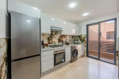a large kitchen with white cabinets and appliances at Luxueuse Apparemment -143 haut standing in Marrakech