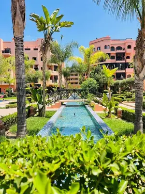 a pool in the middle of a resort with palm trees at Premuim village Marrakech in Marrakech