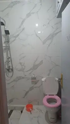 a bathroom with a pink toilet and a marble wall at الأزهار in Marrakech