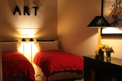 a bedroom with two beds with red sheets and a lamp at Riad MONDRIAH in exclusivity only for you in Marrakech