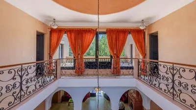 a balcony with orange curtains and a window at la villa du golf in Sfiani