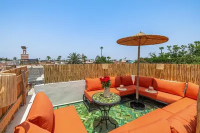 a patio with an orange couch and an umbrella at Riad Symba Exclusive with New Heated Pool and Breakfast Included in Marrakech