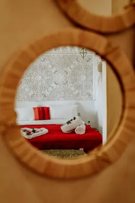 a bedroom with a red bed with white walls at Dar Inara in Marrakech