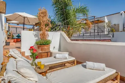a patio with two beds and an umbrella at Riad 5 sens in Marrakech