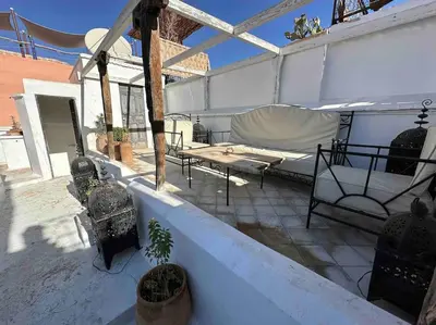 a patio with a bench and a table on a roof at Dar Hatim in Marrakech