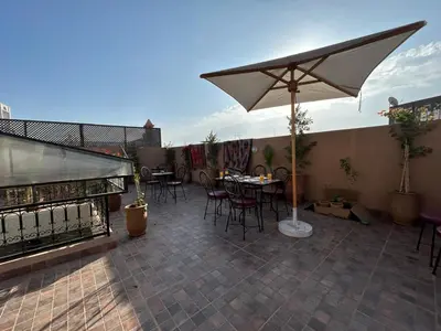 a patio with tables and chairs and an umbrella at Riad Ramadan House Marrakech in Marrakech