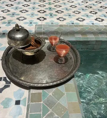 a tray with a tea pot and two glasses in a pool at Riad Panthera, Médina in Marrakech