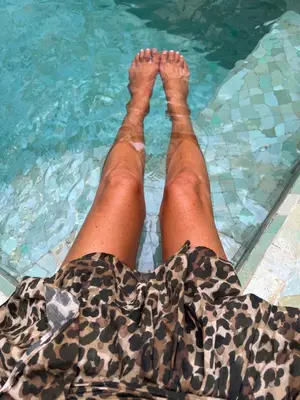 a person with their feet in a swimming pool at Riad Panthera, Médina in Marrakech