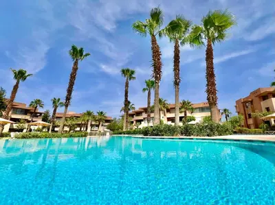 a large swimming pool with palm trees in the background at Prestigia Apart 29 in Marrakech