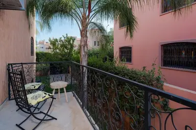 a balcony with a chair and a palm tree at Beautiful Central Marrakech Villa in Marrakech