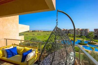 a hammock on a balcony with a view of a pool at Appartement prestigia Jad in Marrakech