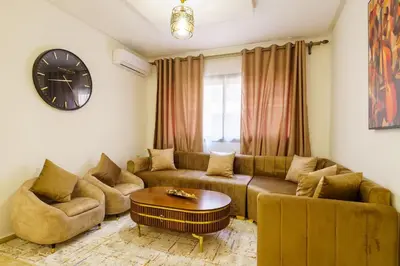a living room with a couch and a table and a clock at Luxury Appartement Cosy 2BR City center Secure Parking Wifi in Marrakech