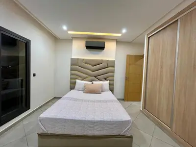 a bedroom with a bed and a tv on the wall at Stylisches City-Apartment im Herzen von Marrakech Gueliz in Marrakech