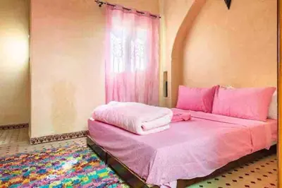 a pink bed in a room with a window at Al Qaria Assiyahia Riad Fadil 44 in Marrakech