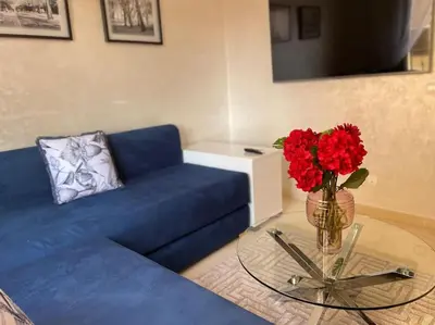 a living room with a blue couch and a glass table with red flowers at Stylish & Comfy Gem 5 Star Location Balcony in Marrakech