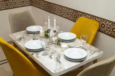 a dining table with plates and candles and yellow chairs at Boho Haven Hivernage - Plein centre ville in Marrakech