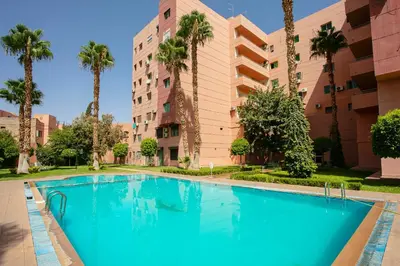 a swimming pool in front of a building with palm trees at A Touch of Marrakchi Magic - Marrakech in Marrakech