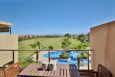 a balcony with a table and a view of a pool at Appartement Prestigia - Golf - Piscine - Restaurants in Marrakech