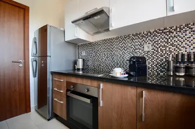 a kitchen with a black counter top and a refrigerator at Appartement Prestigia - Golf - Piscine - Restaurants in Marrakech