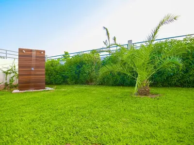 a green yard with a wooden structure and a palm tree at Villa Alanaé piscine chauffée in Douar Bellouk