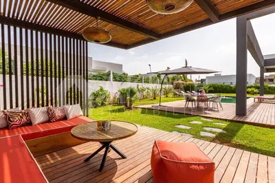 an outdoor patio with a red couch and a table at Villa Alanaé piscine chauffée in Douar Bellouk
