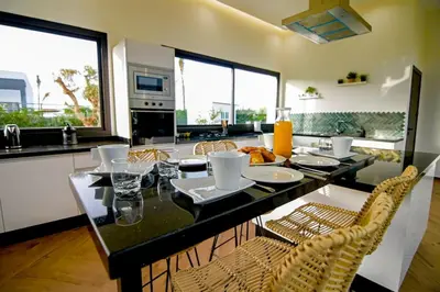 a kitchen with a table with chairs and a counter top at Villa Alanaé piscine chauffée in Douar Bellouk