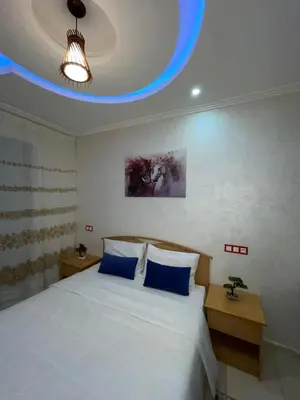 a bedroom with a large white bed with blue pillows at COZY Appartement in Marrakech