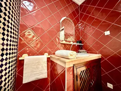 a red tiled bathroom with a sink and a mirror at Triplex spacieux et familial avec une vue panoramique in Marrakech