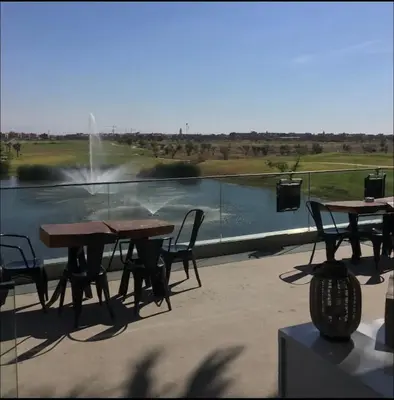 a patio with tables and chairs in front of a fountain at Appartement exceptionnel avec golf in Marrakech