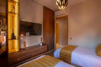 a bedroom with two beds and a flat screen tv at Appartement exceptionnel avec golf in Marrakech