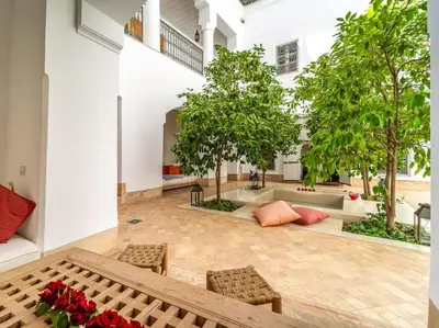 a courtyard with trees and chairs in a building at Peaceful Oasis Authentic Riad in Marrakech