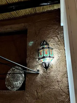 a light on the side of a wall with a lamp at 2 Habitaciones en magnifico riad in Marrakech