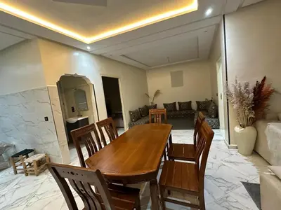 a wooden table and chairs in a living room at Maison meublé 3 pièces avec Piscine in Marrakech