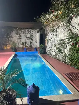 a swimming pool in a backyard at night at Maison meublé 3 pièces avec Piscine in Marrakech