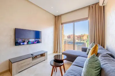 a living room with a blue couch and a tv at MARJANA Luxe appartement in Marrakech