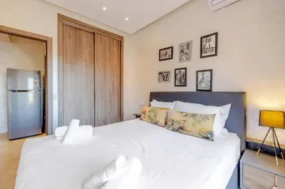 a bedroom with a large white bed with a refrigerator at MARJANA Luxe appartement in Marrakech