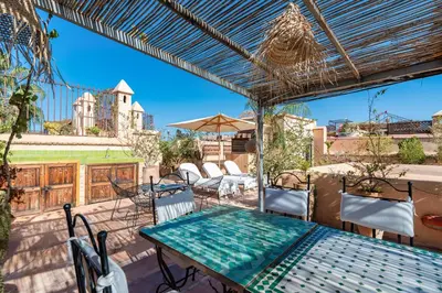 a patio with a table and chairs and an umbrella at Riad Banafsaj - Exclusif - 20mn de Jamaa Al Fnaa in Marrakech