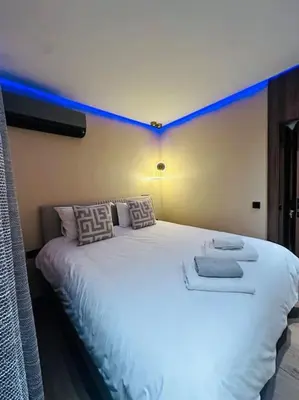 a bedroom with a large white bed with blue lighting at Sublime Appartement 1 chambre WIFI à Marrakech in Marrakech