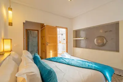 a bedroom with a large bed with blue pillows at Riad SWAN-exclusif - Piscine chauffée - Petit déjeuner in Marrakech