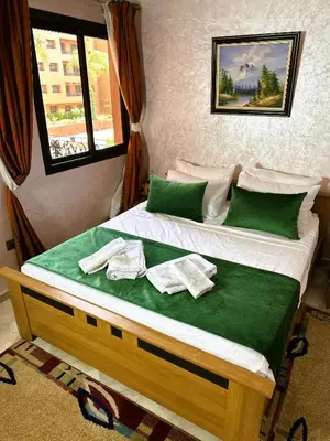 a bed with green sheets and towels on it at Calme et cozy avec piscine in Marrakech