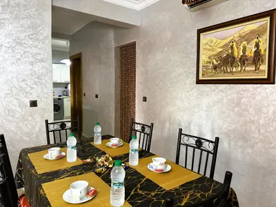 a dining room with two tables with chairs and water bottles at Calme et cozy avec piscine in Marrakech