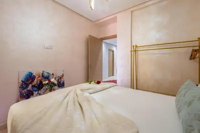 a bedroom with a white bed with a painting on the wall at L'Havre de paix de Guéliz au Coucher de Soleil in Marrakech
